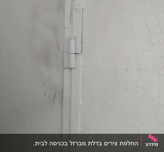 תקריב של ציר ברזל מולחם למסגרת ממתכת צבועה לבן